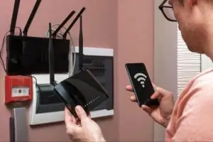 Homeowner setting up a Wi-Fi router while comparing internet providers to choose the best home internet service.